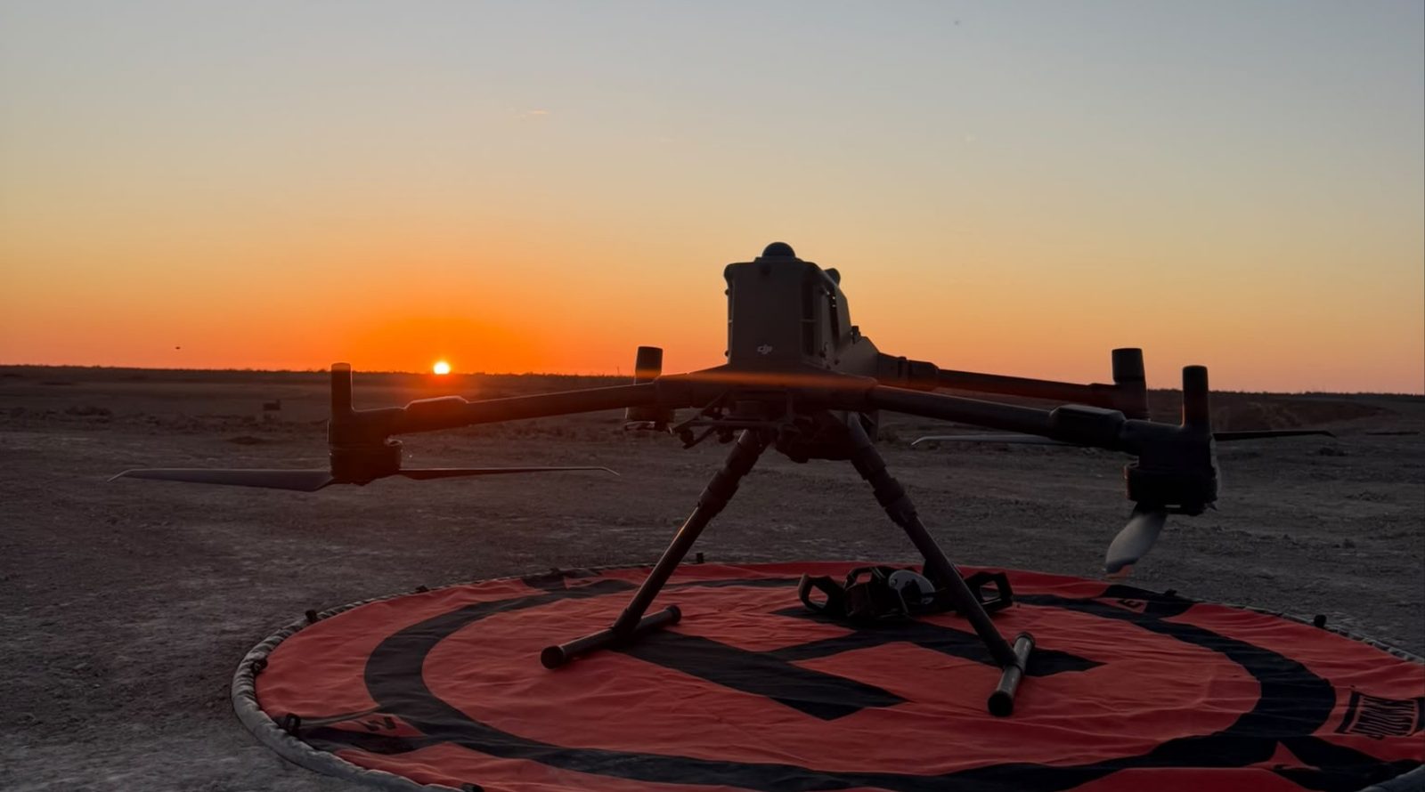 DJI Matrice enterprise drone on a landing pad at sunrise before a solar farm thermography flight