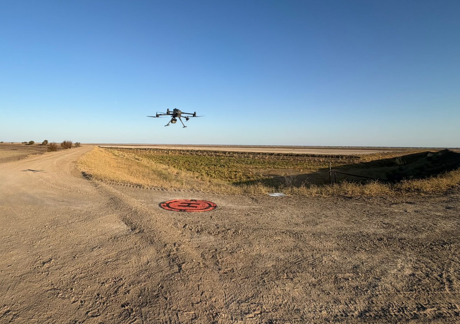 DJI Matrice 400 enterprise drone in flight above a mine haul road with a landing pad below